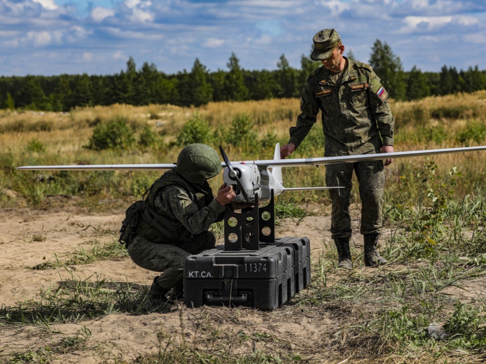 Военнослужащий проверяет беспилотник на подставке, рядом стоит второй